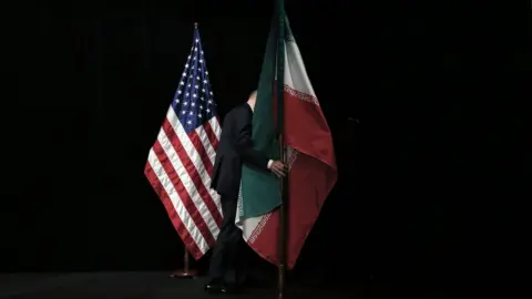 AFP Member of staff removes the Iranian flag from the stage after a group picture with foreign ministers and representatives of Unites States, Iran, China, Russia, Britain, Germany, France and the European Union during the Iran nuclear talks at Austria International Centre in Vienna, Austria on 14 July 2015.