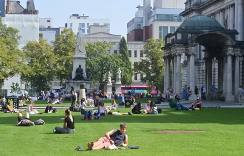 Pacemaker Press People enjoy the sun outside Belfast City Hall