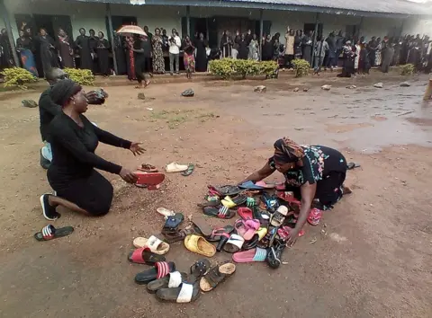 Reuters Parents of students abducted at Bethel Baptist High School pray for their safe return around discarded shoes left behind by the children, in Kaduna, Nigeria July 9, 2021.