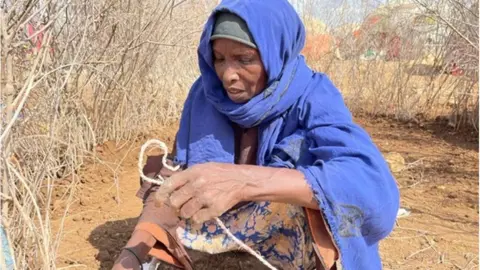 BBC/ Ed Habershon Habiba (a woman wearing a blue headscarf) is seen with a piece of string