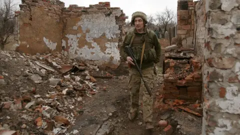 Getty Images A Ukrainian serviceman patrols near the frontline with Russia backed separatists near small city of Marinka, Donetsk region. Photo: 12 April 2021