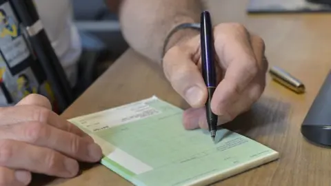 PA Media File image of a GP writing out a prescription on a blank pad of paper