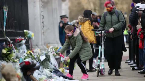 PA Media Child places flowers outside Buckingham Palace