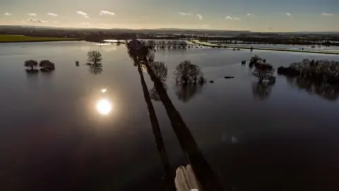 Ben Birchall A car turns around to avoid floodwaters on Langport Road, near Muchelney, Somerset.