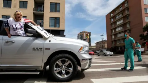 Alyson McClaran Protesters in Denver pushing for an economic reopening are met with counter-protesters dressed in scrub