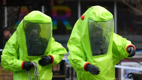 Getty Images Two people wearing green protective suits involved in the investigation in Salisbury.