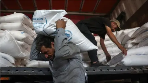 Getty Images UN aid unloaded from a truck near Bab al-Hawa (file photo)