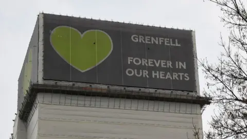 Reuters Top of Grenfell Tower wrapped in banner saying "Forever in our hearts"