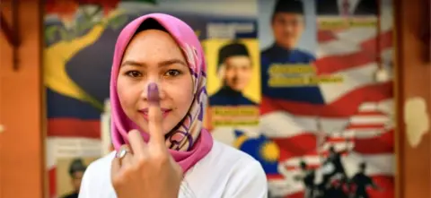 AFP A woman shows her finger after voting in Malaysia