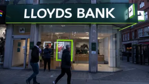 Getty Images People walk past Lloyds bank branch