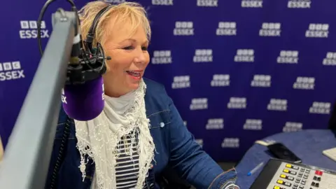 Stuart Woodward/BBC Sadie Nine behind the presenter's microphone