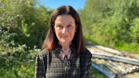 Steve Hubbard/BBC Woman with long dark hair outdoors surrounded by trees