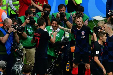 Mladen Antonov/AFP Croatia's forward Mario Mandzukic (L) shakes hands with AFP photographer Yuri Cortez (C) after falling on him with teammates while celebrating their second goal during the Russia 2018 World Cup semi-final football match between Croatia and England at the Luzhniki Stadium in Moscow on 11 July 2018.