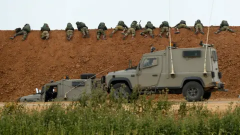 AFP Israeli soldiers lie along an earth barrier along the border with the Gaza strip in the southern Israeli kibbutz of Nahal Oz on March 30, 2018