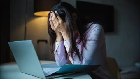 NoSystem images/ Getty Images woman with head in hands on laptop