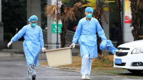 Reuters Medical staff carry a box as they walk at the Jinyintan hospital, where the patients with pneumonia caused by the new strain of coronavirus are being treated, in Wuhan, Hubei province