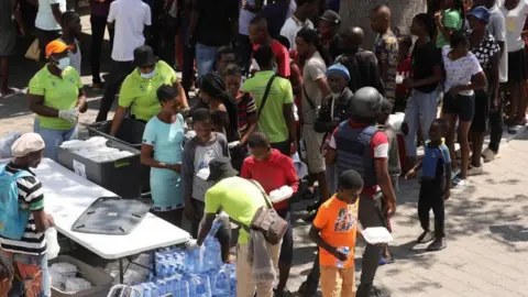 Reuters Residents who fled violence gather to receive meals at a school being used as shelter as the government declared state of emergency amid violence, in Port-au-Prince, Haiti, March 4, 2024.