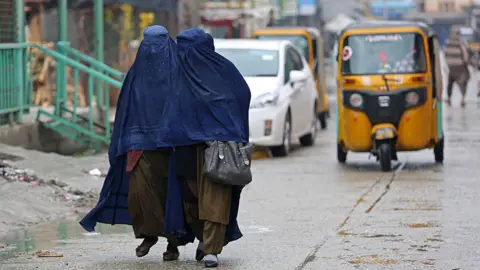 AFP women walking down a street wearing burkas