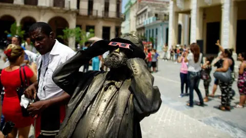 Reuters A street performer looks towards the sky as enthusiasts gather in Old Havana for the partial solar eclipse in Cuba August 21, 2017.