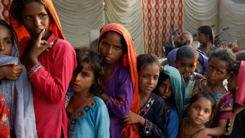 People queue for food aid on 14 September after flooding in Sehwan, Pakistan.