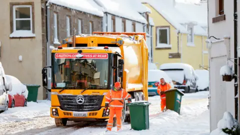 Getty Images Bin men work in the snow