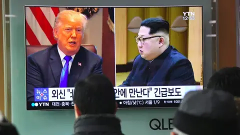 Getty Images People watch a television news report showing pictures of US President Donald Trump (L) and North Korean leader Kim Jong Un at a railway station in Seoul on March 9, 2018.