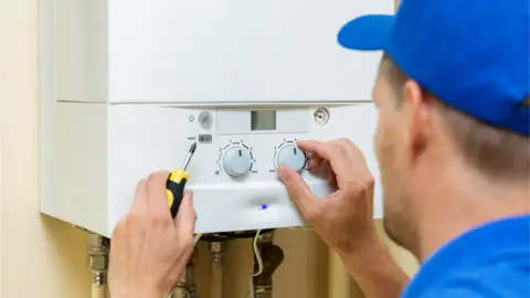 Getty Images Plumber working on gas boiler
