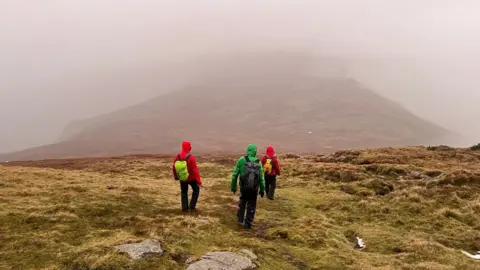 Keswick Mountain Rescue Team Three volunteers walking on fell in mist