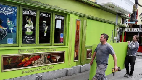 PA/Brian Lawless Workers board up a pub in Dublin