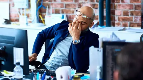 Getty Images Man at desk looking stressed out