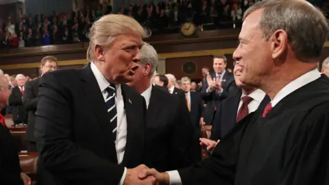 JIM LO SCALZO/AFP/Getty Images Trump shakes Justice Roberts' hand