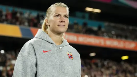 Getty Images Ada Hegerberg walks on the pitch in a grey hoody and blonde hair tied in a ponytail