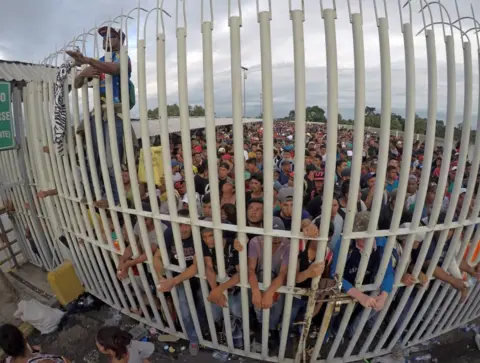 EPA Honduran migrants wait behind a gate after crossing the fence on the border with Guatemala to enter Mexico