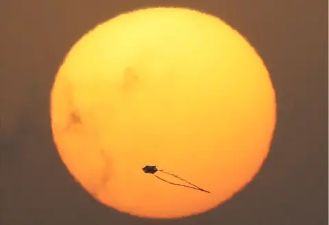 Reuters A kite hovering in the air is silhouetted against a low, full sun.