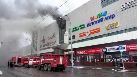 AFP Emergency vehicles outside a burning shopping centre in Kemerovo, Russia. 25 March 2018