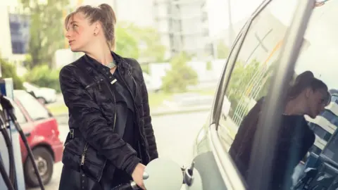 Getty Images Woman refuelling car