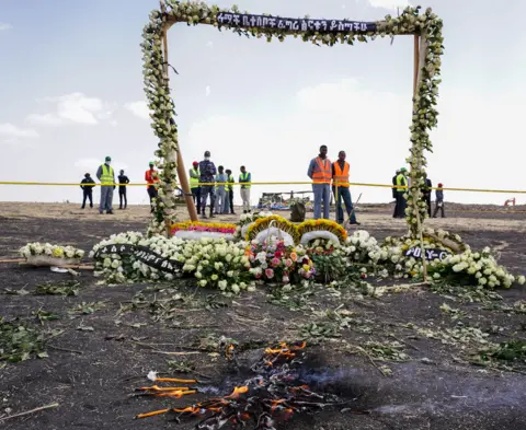 Getty Images Candles burn before a flower adorned memorial arch erected at the site of the Ethiopian Airlines Flight ET302 crash on March 14, 2019 in Ejere, Ethiopia.