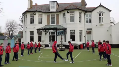 Reuters Pupils greet each other with a foot-to-foot tap instead of shaking hands to avoid the spread of coronavirus, in Hove, Britain