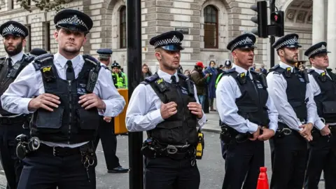 Getty Images Police officers standing in a row in the middle of a road