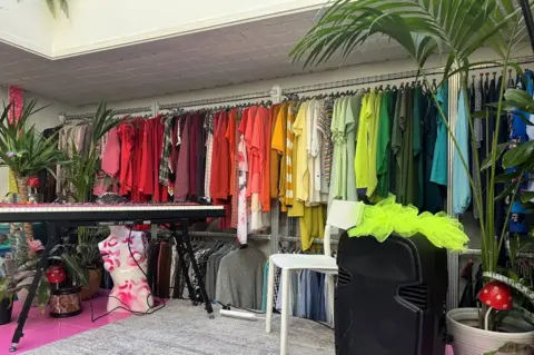 Colourful clothes hanging in swap shop at Green House