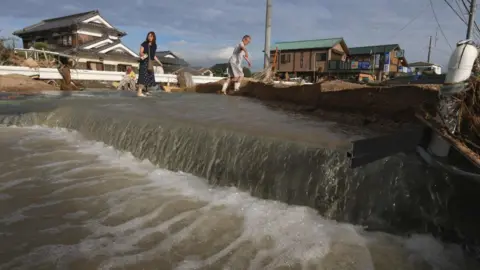 Getty Images Residents cross an area still flooded in Kurashiki, Okayama prefecture on July 9, 2018