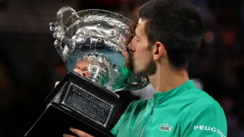 Reuters Novak Djokovic kisses a trophy he was awarded for winning last year's Australian Open title