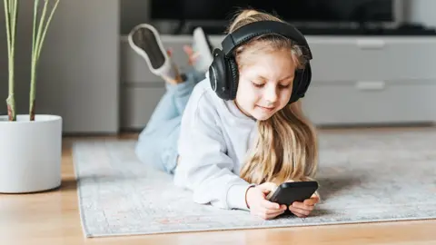 Getty Images Child using a phone with headphones