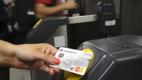 PA Media A customer at a the ticket barrier at Canary Wharf underground station