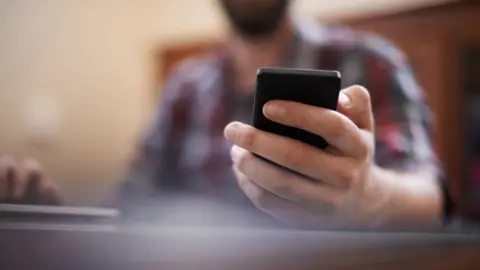 Getty Images Man holding mobile phone