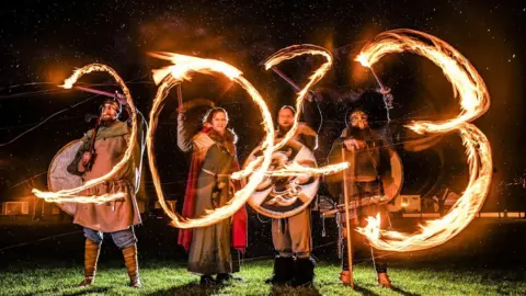 PA Media Viking reenactors use flaming torches to write 2023 during the Flamborough Fire Festival, a Viking themed parade in aid of charities and local community groups, held on New Year's Eve in Flamborough near Bridlington, Yorkshire. Picture date: Saturday December 31, 2022.
