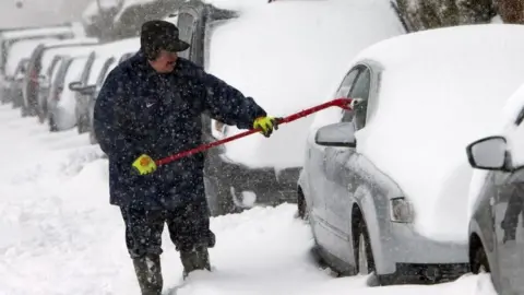 PA Man clearing snow from car in Glasgow