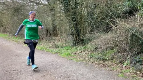 Tom WIlliams/BBC Apryl Hammett running on a dirt track in a park