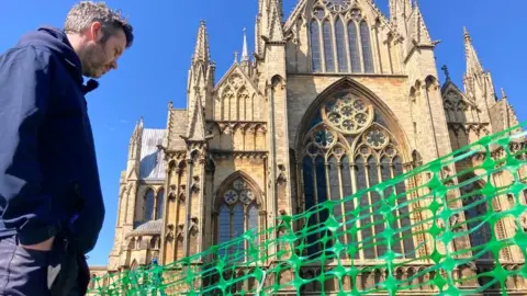 BBC Man looking into an empty ground at Lincoln Cathedral