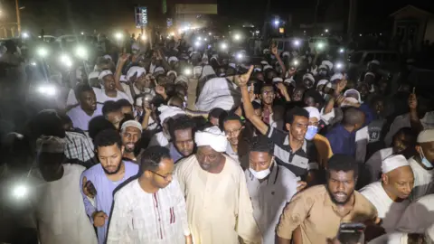 Getty Images Crowds gather at night holding phones to provide light at the funeral of Zubair Ahmed al-Hassan, the secretary general of the Islamic Movement in Khartoum, Sudan - Saturday 1 May 2021